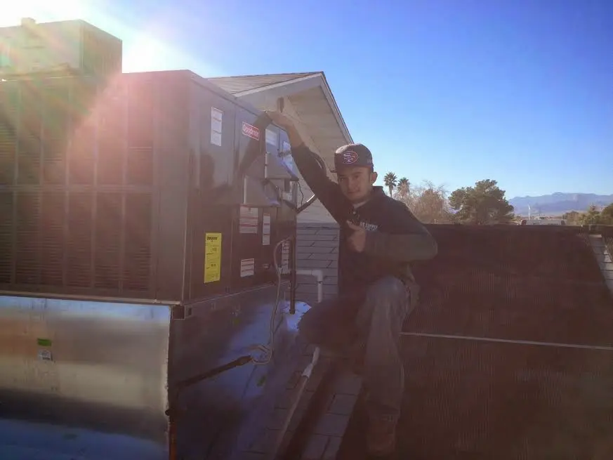 HVAC technician performing AC Tune-Up on a rooftop unit in West Des Moines
